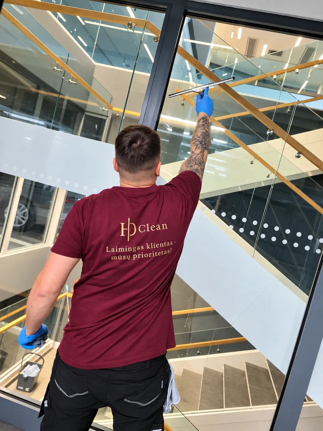 HD Clean darbuotojas valo stiklinę pertvarą biuro laiptinėje